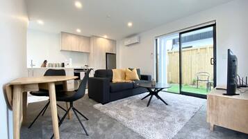 A modern living room with a sofa, coffee table, and dining area.