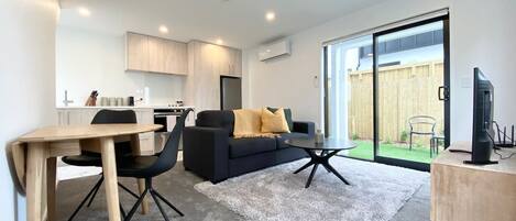 A modern living room with a sofa, coffee table, and dining area.