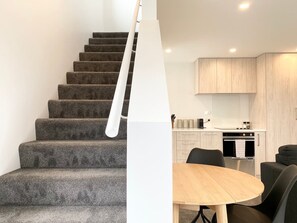 Un interno moderno con una scala, una zona pranzo e una cucina.