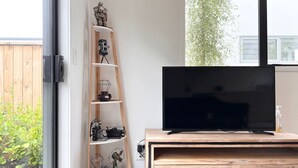 Una sala moderna con una unidad de entretenimiento de madera, un televisor de pantalla plana y una estantería escalonada decorativa con varios objetos.