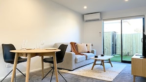 Ein modernes Wohnzimmer mit einer Couch, einem Couchtisch und einem Esstisch mit Stühlen.