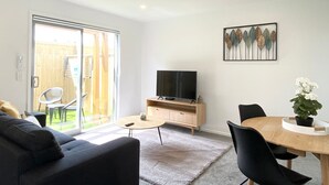Un salon moderne comprenant un téléviseur, un canapé, une table à manger et des chaises.