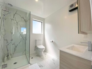 A modern bathroom with a glass shower enclosure, a toilet, and a sink with a wooden vanity. - Salisbury courtyard retreat with a workspace in Christchurch (Christchurch)
