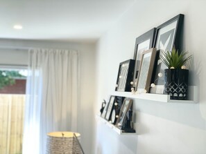 A wall-mounted shelf with framed pictures, a small potted plant, and decorative items.
