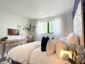 A bedroom with a bed, bedside table, and a window with curtains. - Bambina design retreat opposite Hagley Park in Christchurch (Christchurch)