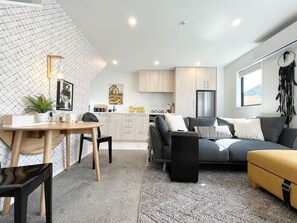 A modern living space with a dining area, a sofa, and a kitchen. - Bambina design retreat opposite Hagley Park in Christchurch (Christchurch)
