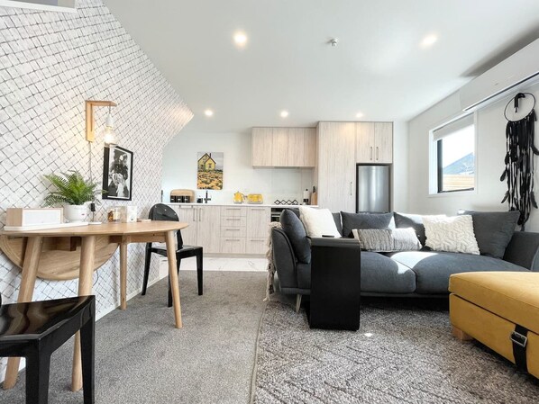 Un espacio de estar moderno con comedor, sofá y cocina.