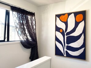 A room with a window, a white bench, and a framed abstract painting on the wall. - Bambina design retreat opposite Hagley Park in Christchurch (Christchurch)