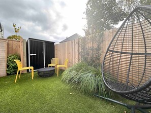 A backyard with artificial grass, a black gate, wooden fence, and a hanging chair. - Bambina design retreat opposite Hagley Park in Christchurch (Christchurch)