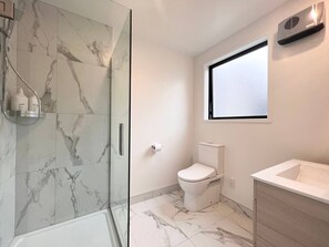 Ein modernes Badezimmer mit Duschkabine aus Glas, Toilette und Waschbecken.