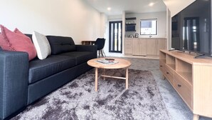 A modern living room with a dark sofa, a round coffee table, and a TV on a wooden stand.