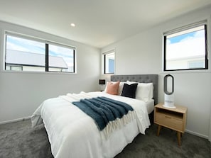 A bedroom with a bed, bedside table, and a nightstand with a mirror.