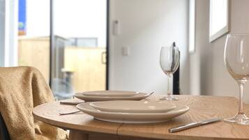 A dining table with plates, cutlery, and wine glasses set for two.
