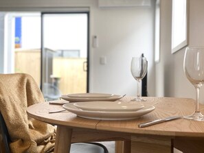 A dining table with plates, cutlery, and wine glasses set for two.