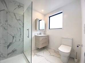 A modern bathroom with a glass shower enclosure, a white vanity with a mirror, and a toilet.
