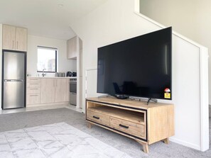 Una cucina moderna con televisore integrato, mobili in legno e frigorifero.