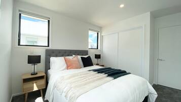 Un dormitorio con cama, mesitas de noche y ventana.
