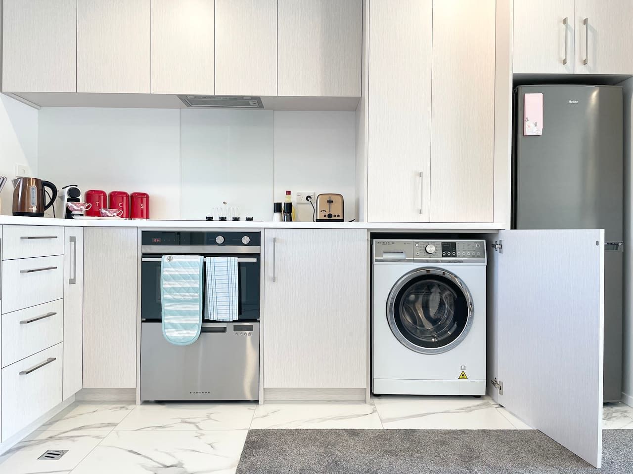 Une cuisine moderne équipée d’un four encastré, d’un lave-linge et d’un réfrigérateur.