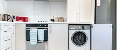 Une cuisine moderne équipée d’un four encastré, d’un lave-linge et d’un réfrigérateur.