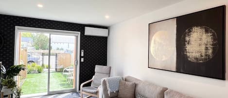 En moderne stue med en grå sofa, et hvidt sofabord og et stort abstrakt billede på væggen.