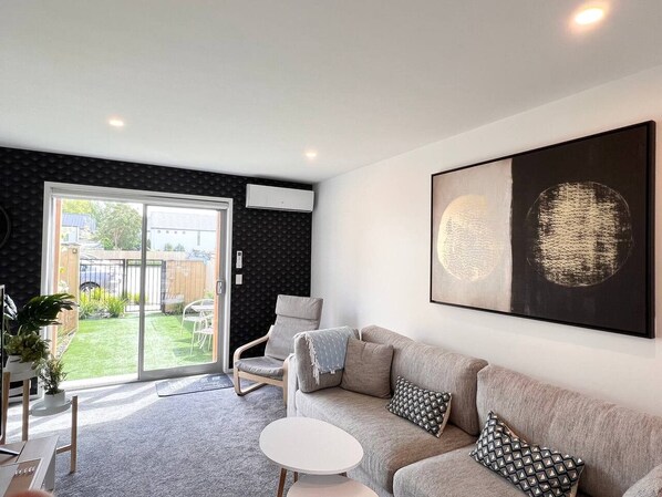 A modern living room with a grey sofa, a white coffee table, and a large abstract painting on the wall.