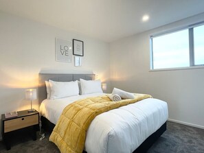 Una habitación de hotel con cama, mesitas de noche, una ventana y decoración en la pared.