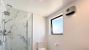 Een moderne badkamer met een douchecabine van glas, een toilet en een wastafel.