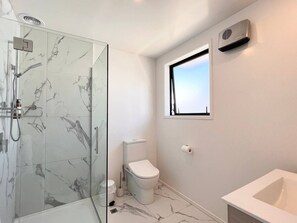 Un baño moderno con cabina de ducha de vidrio, inodoro y lavabo.