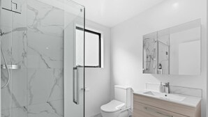 Une salle de bain moderne avec une douche à parois de verre, des toilettes et un meuble-lavabo avec un miroir.