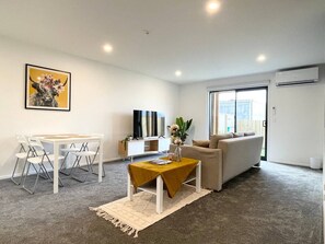 Un salon comprenant un canapé, une table basse, un téléviseur et un coin repas avec des chaises et une table.