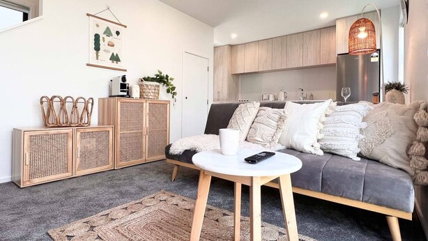 Ein modernes Wohnzimmer mit einem grauen Sofa, einem weißen Couchtisch und einem gewebten Teppich.