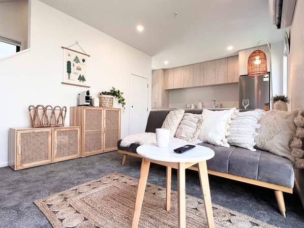 A modern living room with a grey sofa, a white coffee table, and a woven rug.