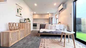 A modern living room with a sofa, a coffee table, and a kitchen in the background.