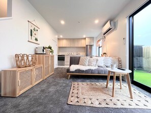 A modern living room with a sofa, a coffee table, and a kitchen in the background.