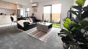 A modern living room with a black leather sofa, a coffee table, and a large window.