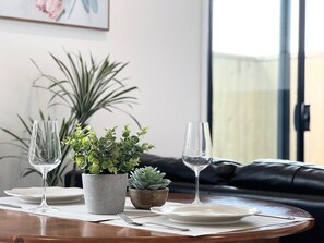A dining table set with two wine glasses, a plate, and two potted plants.