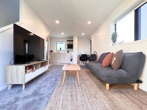 Una sala de estar moderna con una televisión de pantalla plana, un sofá gris y una mesa de centro.