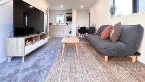 A modern living room with a flat-screen TV, a grey sofa, and a coffee table.