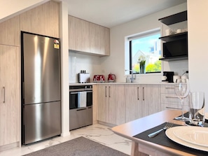 A modern kitchen with a stainless steel refrigerator, a built-in oven, and a dining area with a table set for two.