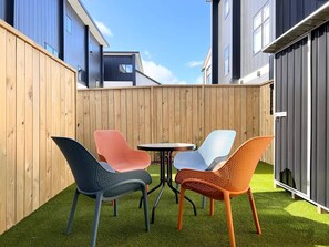 A patio with a round table and four colorful chairs.