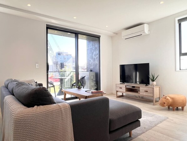 A modern living room with a sofa, a coffee table, a TV, and a piggy bank.