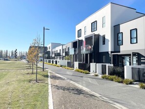 A modern residential building with a clean, minimalist design, featuring large windows and a flat roof.
