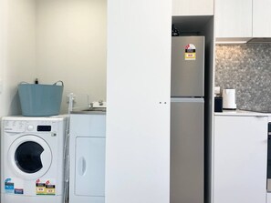 Een kleine keuken met een wasmachine, een koelkast en een magnetron.