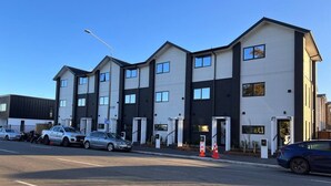 Un immeuble à étages doté d’une architecture moderne, caractérisé par une combinaison de panneaux blancs et de panneaux de couleur foncée.