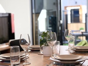 Een eettafel gedekt met borden, glazen en een vaas met een plant.