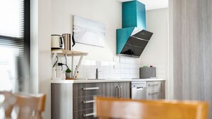 Eine moderne Küche mit weißen Fliesen, Edelstahlgeräten und einer Türkis-farbenen Akzentwand.