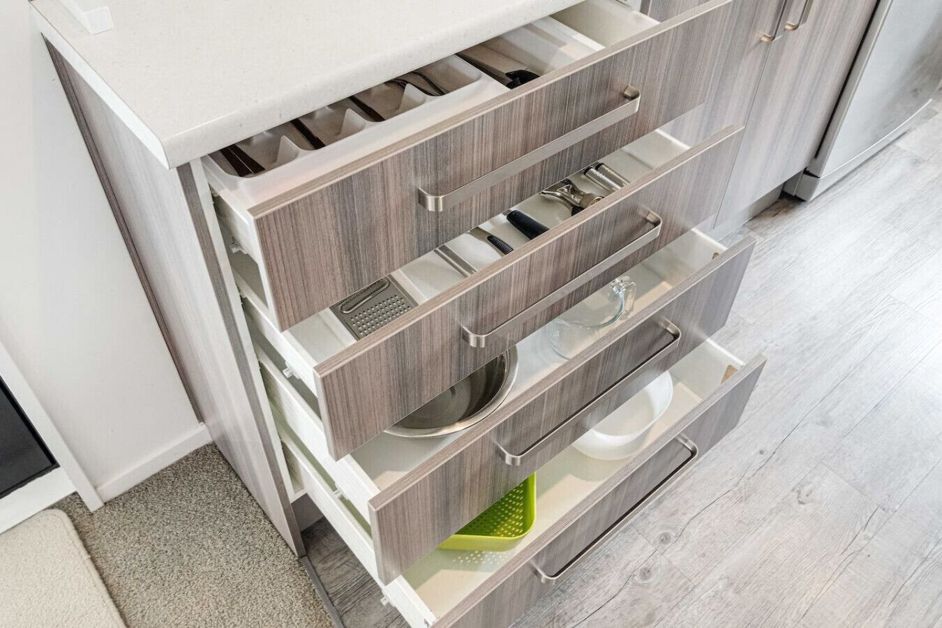 Une cuisine équipée d’appareils électroménagers intégrés, de meubles de rangement en bois et d’un plan de travail.