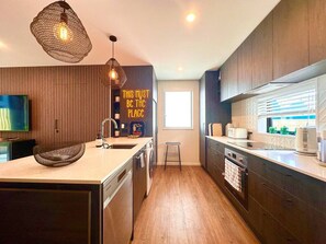 Una cocina moderna con armarios de madera, una isla grande e iluminación colgante.