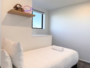 A small, neatly arranged bedroom with a single bed, a window, and a shelf with a stuffed toy. - Lichfield city stay with a super king suite in Christchurch (Christchurch)