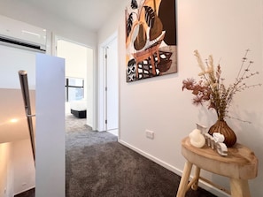 A hallway with a modern kitchen area, a dining table, and a decorative wall piece. - Lichfield city stay with a super king suite in Christchurch (Christchurch)